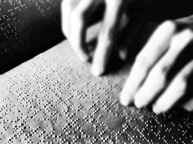 World Braille Day Black-and-white image of two hands reading Braille.